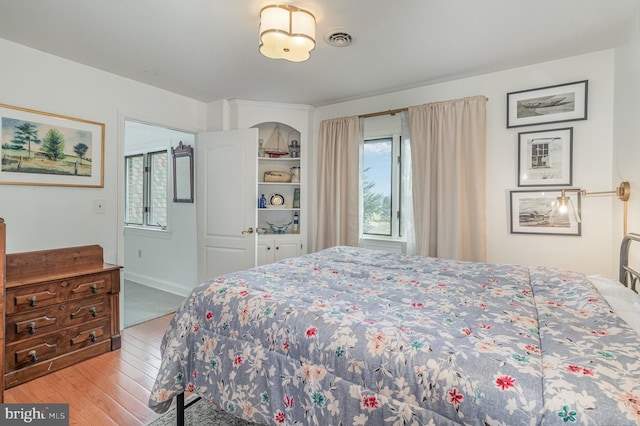 bedroom featuring visible vents, baseboards, and wood finished floors