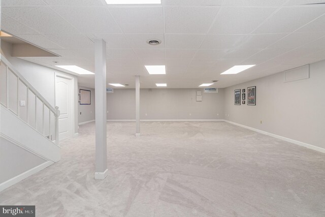 finished basement with stairway, visible vents, baseboards, a drop ceiling, and light colored carpet