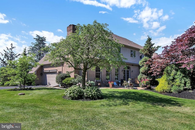 back of property featuring brick siding, a chimney, an attached garage, and a lawn