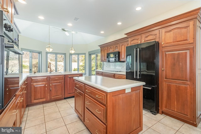 kitchen featuring a kitchen island, a sink, ceiling fan, black appliances, and light countertops