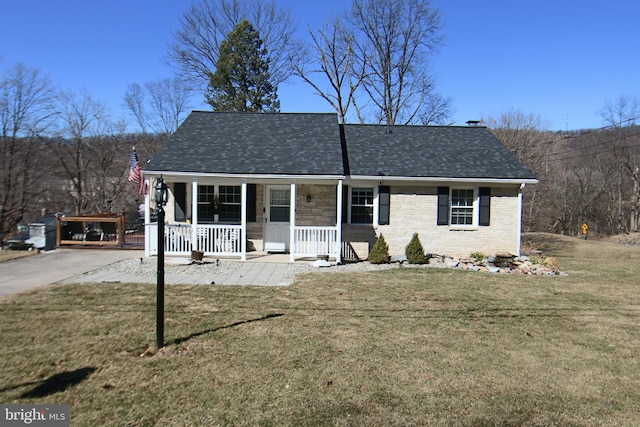 view of front of house with a porch, a front yard, brick siding, and a shingled roof