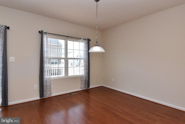 unfurnished room featuring visible vents, dark wood-type flooring, and baseboards