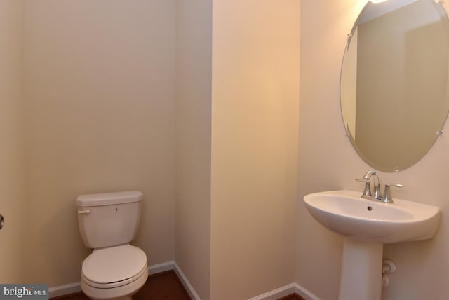 half bathroom featuring a sink, baseboards, and toilet