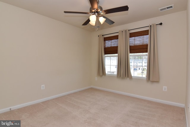 empty room with visible vents, light carpet, baseboards, and ceiling fan