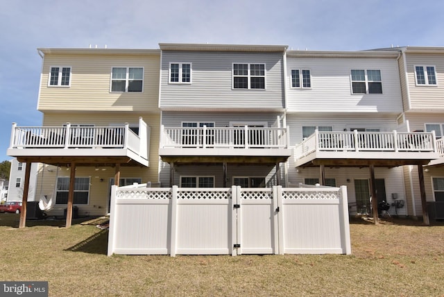 rear view of property featuring a gate, a yard, and fence