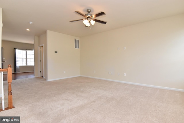 unfurnished room with visible vents, light colored carpet, baseboards, and ceiling fan