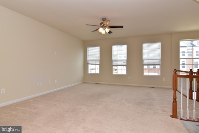 unfurnished room featuring light colored carpet, baseboards, and a ceiling fan