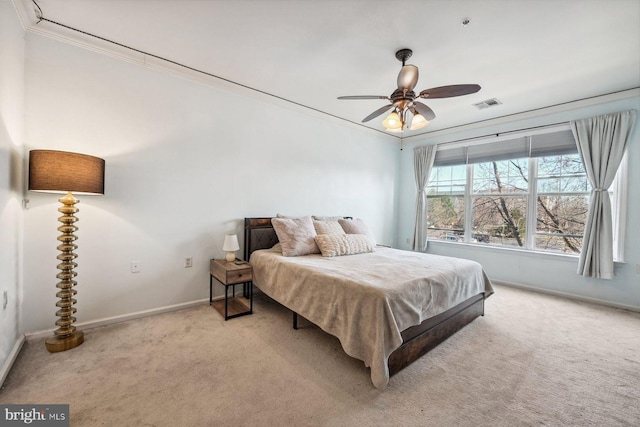 carpeted bedroom with visible vents, baseboards, ornamental molding, and a ceiling fan