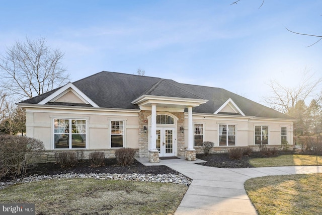 view of front of home featuring a shingled roof, french doors, stone siding, and stucco siding