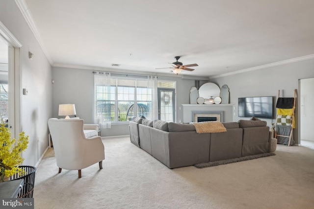 carpeted living room with visible vents, a fireplace, crown molding, and ceiling fan