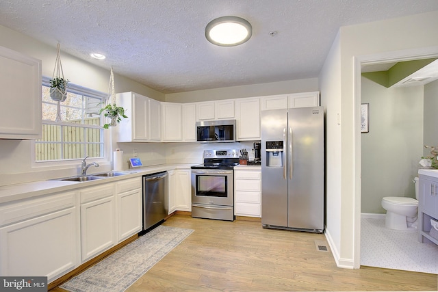 kitchen featuring appliances with stainless steel finishes, white cabinetry, and light wood finished floors