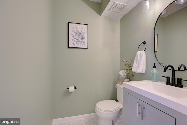 half bathroom featuring visible vents, toilet, vanity, baseboards, and tile patterned floors