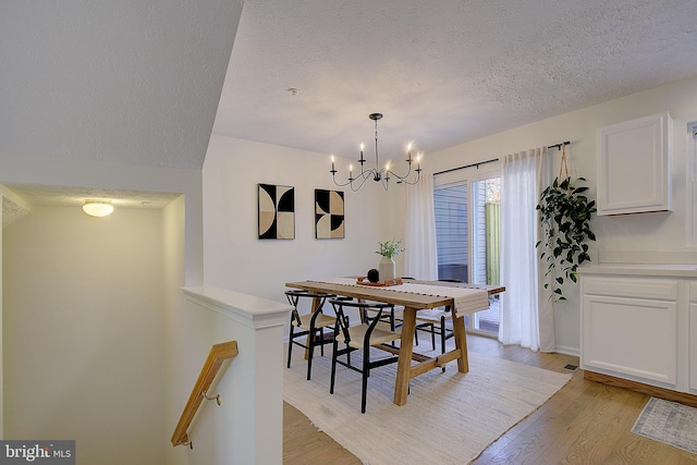 dining room with a chandelier, a textured ceiling, and light wood-style flooring