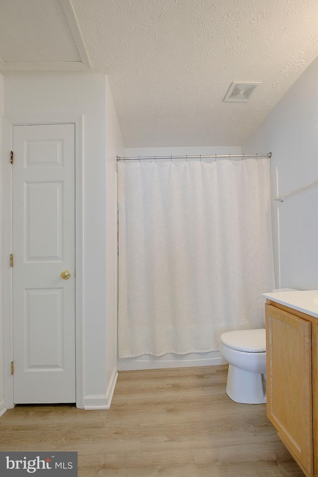 full bath with toilet, visible vents, wood finished floors, and vanity