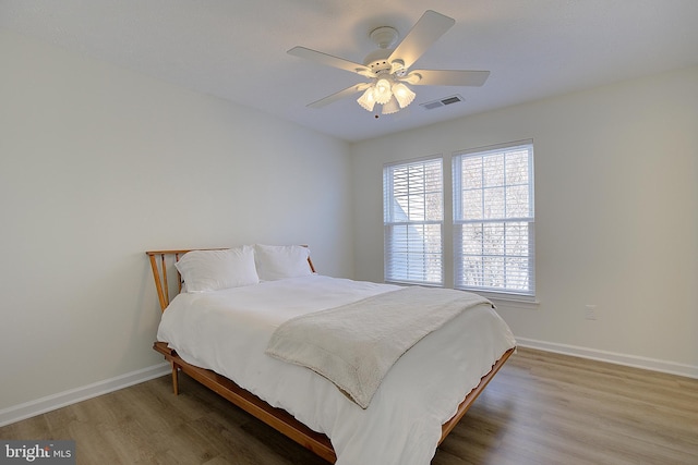 bedroom with baseboards, visible vents, ceiling fan, and wood finished floors