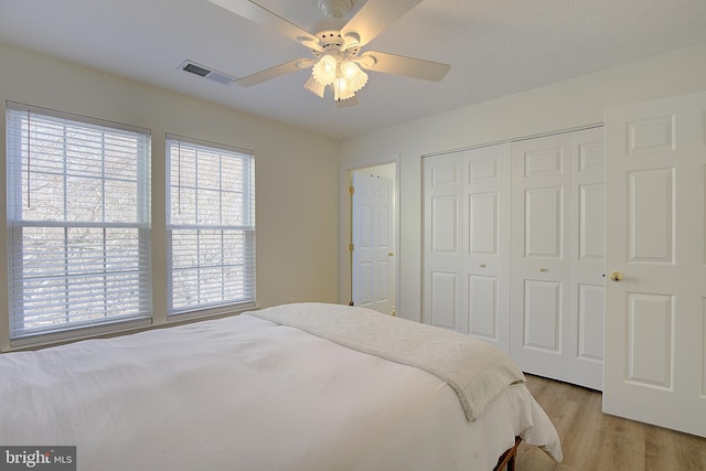 bedroom with ceiling fan, a closet, visible vents, and light wood-style floors