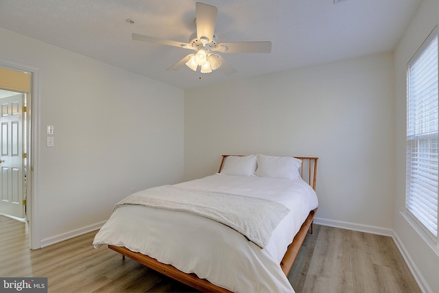 bedroom featuring light wood finished floors, multiple windows, and baseboards