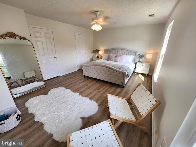 bedroom with baseboards, visible vents, ceiling fan, wood finished floors, and a textured ceiling