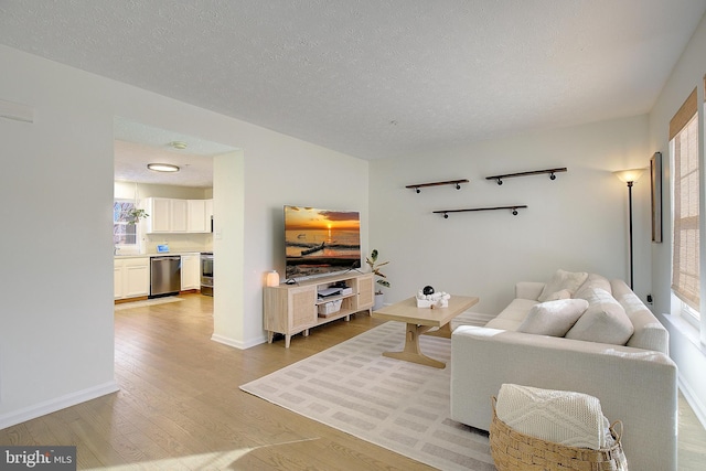 living area featuring baseboards, a textured ceiling, and light wood-style floors