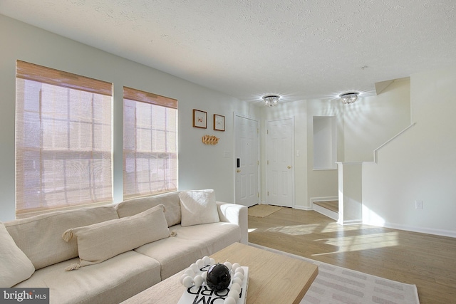 living room featuring light wood finished floors, baseboards, and a textured ceiling