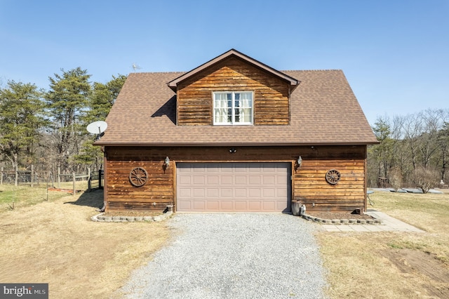 chalet / cabin featuring gravel driveway, fence, a garage, and roof with shingles