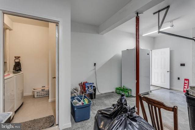 garage featuring baseboards, independent washer and dryer, and freestanding refrigerator