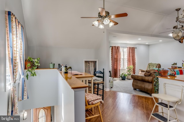 living room with ceiling fan, wood finished floors, and vaulted ceiling