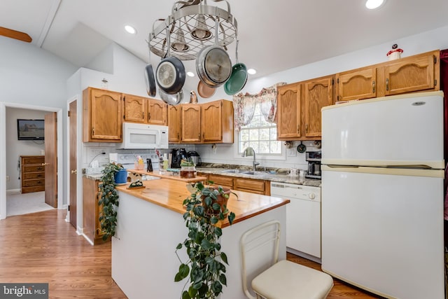 kitchen featuring a center island, vaulted ceiling, recessed lighting, white appliances, and a sink