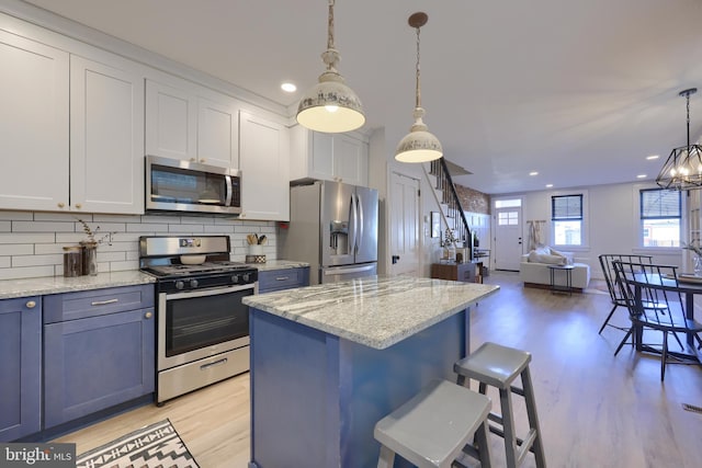 kitchen featuring stainless steel appliances, tasteful backsplash, light wood-type flooring, and a center island