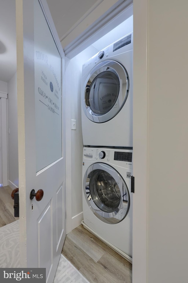 clothes washing area featuring light wood-type flooring, stacked washer and dryer, and laundry area