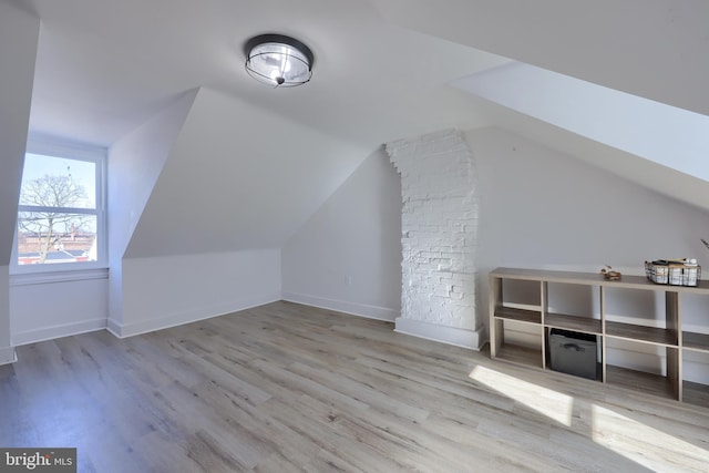 additional living space with vaulted ceiling, wood finished floors, and baseboards