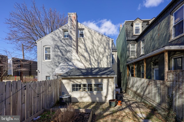 back of house featuring fence, a chimney, and central AC unit