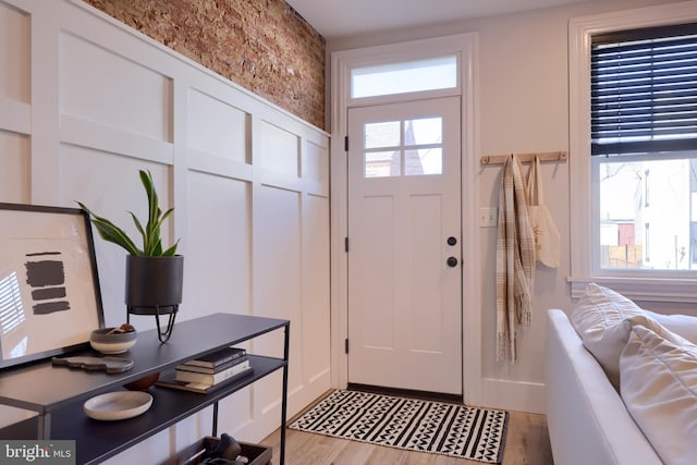 entryway featuring light wood-style flooring, a wealth of natural light, and a decorative wall