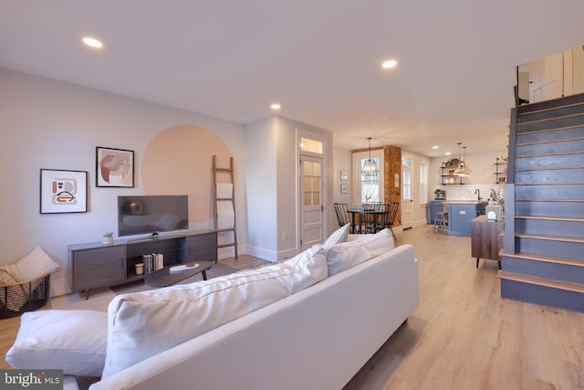 living room with light wood-style flooring, stairway, arched walkways, and recessed lighting