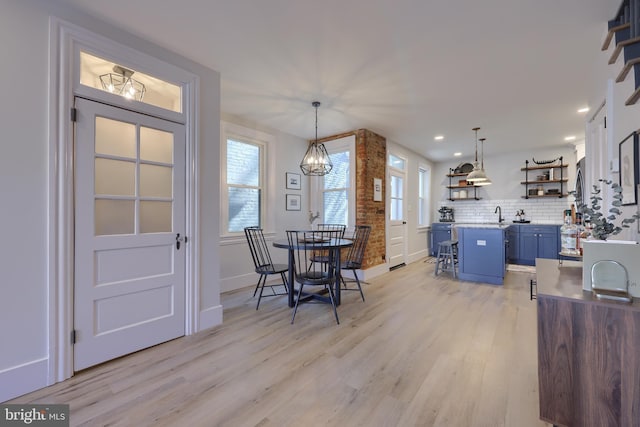 dining area with a notable chandelier, a wealth of natural light, and light wood-style floors