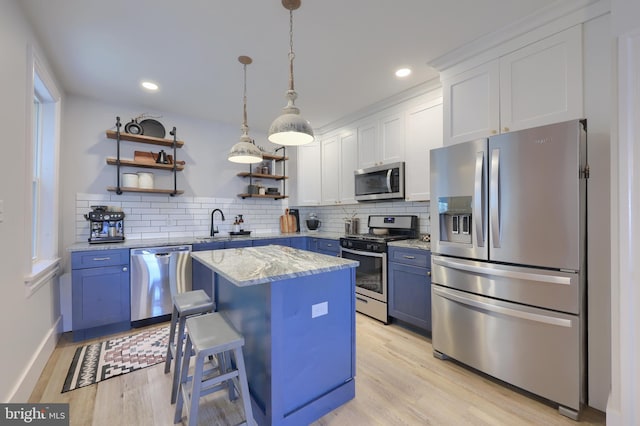 kitchen with stainless steel appliances, open shelves, light wood-style flooring, and blue cabinets