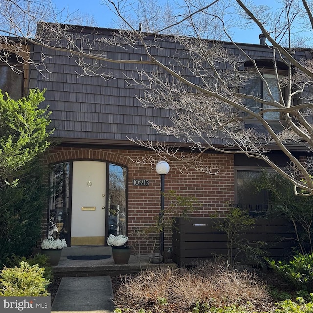 exterior space with brick siding and mansard roof