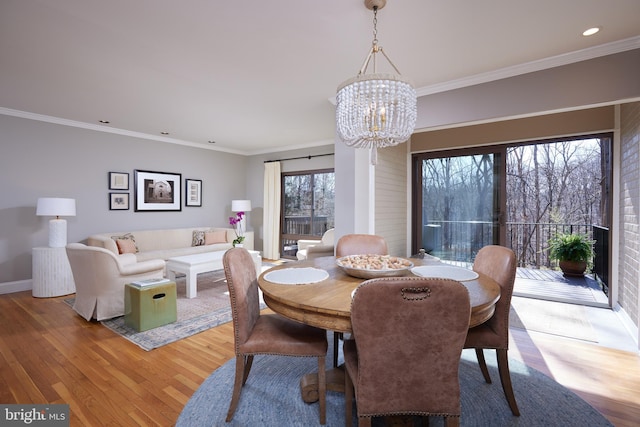 dining room featuring a chandelier, crown molding, baseboards, and wood-type flooring