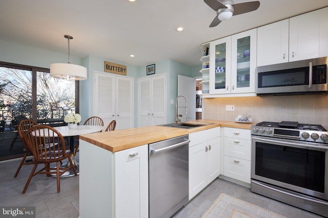 kitchen featuring a sink, stainless steel appliances, a peninsula, and butcher block counters