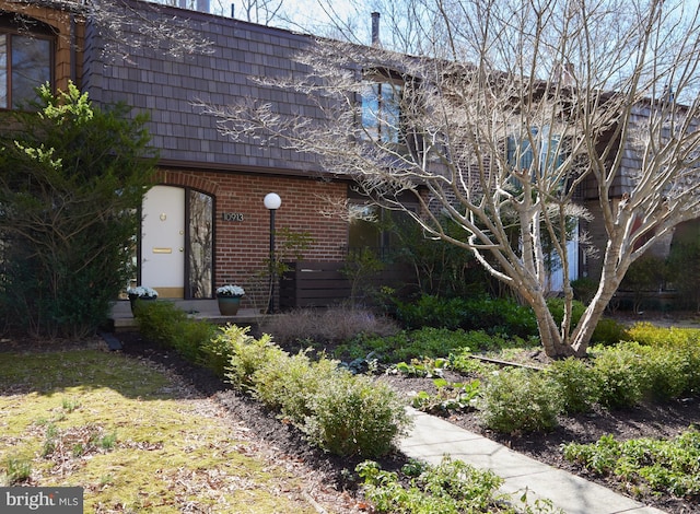 exterior space featuring mansard roof and brick siding