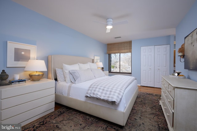 bedroom with a closet, dark wood-type flooring, visible vents, and ceiling fan