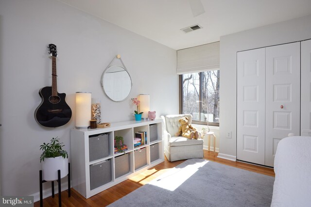 living area with visible vents, baseboards, and wood finished floors