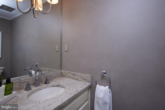 bathroom with a chandelier, vanity, and ornamental molding