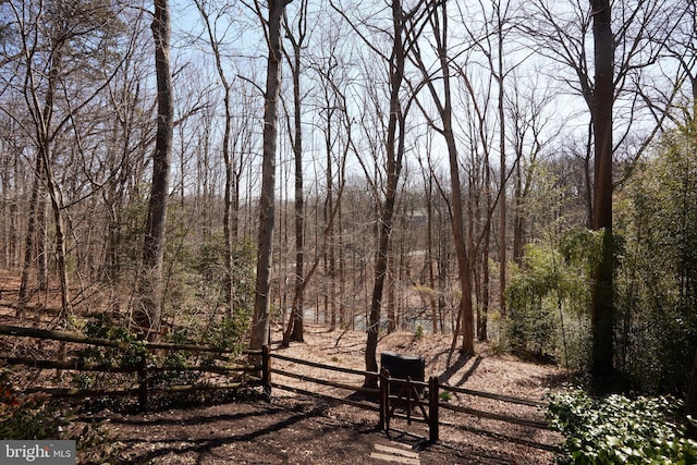 view of yard with a wooded view and fence