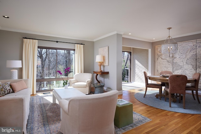 living area with a wealth of natural light, light wood-type flooring, an inviting chandelier, and crown molding