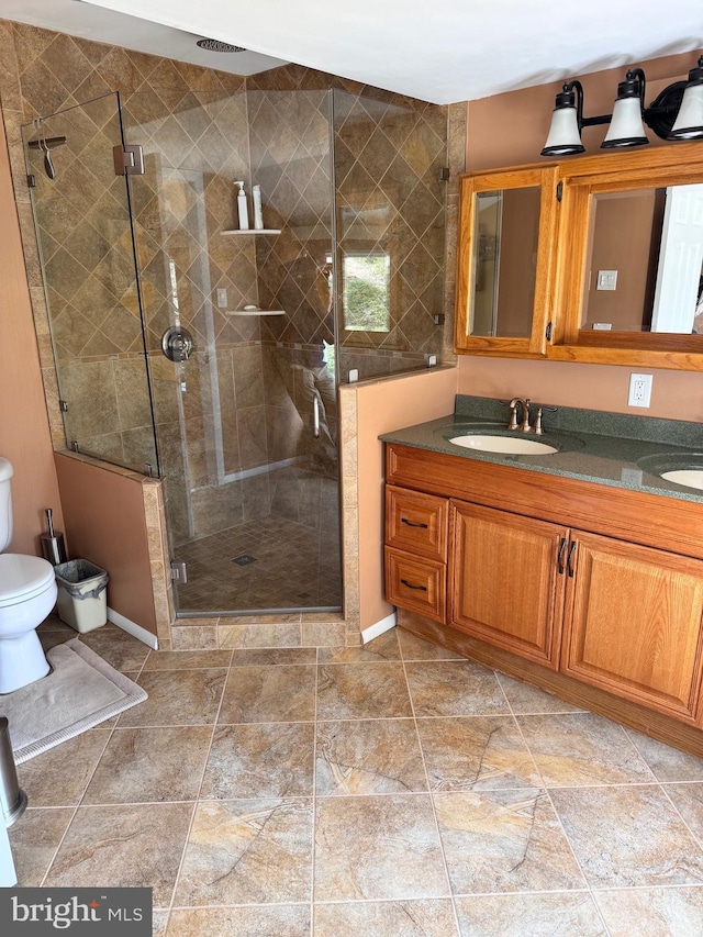 bathroom featuring a sink, toilet, a stall shower, and double vanity