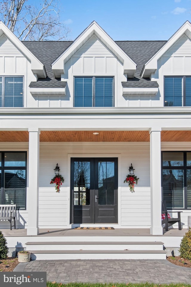 view of exterior entry featuring a shingled roof, board and batten siding, and a porch