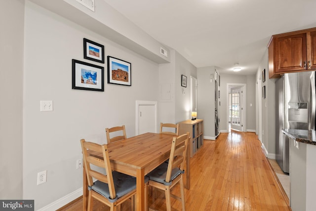 dining space featuring light wood-type flooring, visible vents, and baseboards