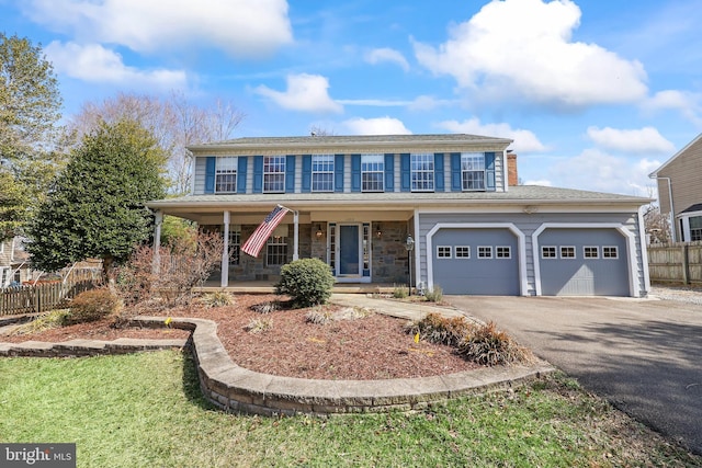 view of front of property featuring fence, covered porch, a garage, stone siding, and aphalt driveway