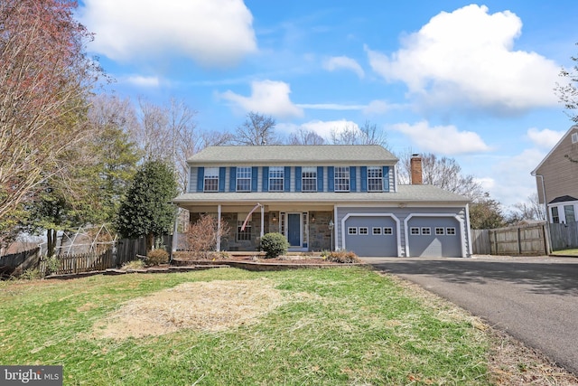 view of front of property with a front yard, fence, driveway, and a chimney